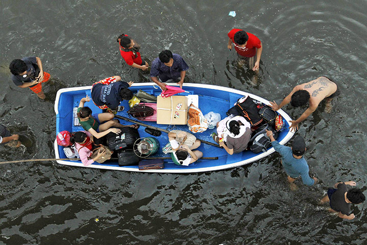 24 hours in pictures: Pathum Thani province, Thailand: People use a boat during an evacuation