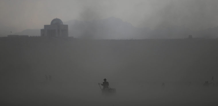 24 Hours: An Afghan man pushes his cart through a sand storm