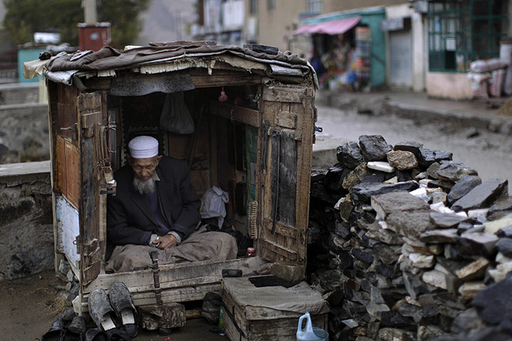 24 Hours: An Afghan shoemaker sits inside his stall waiting for customers