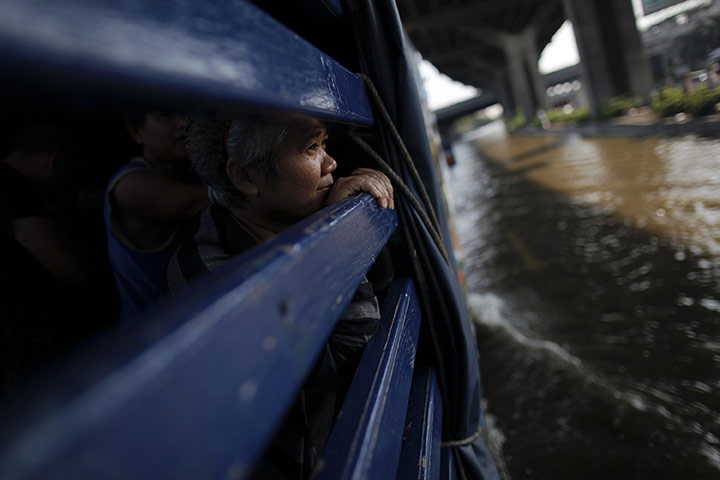 24 hours: Bangkok, Thailand: A woman looks from inside a truck as floods advance