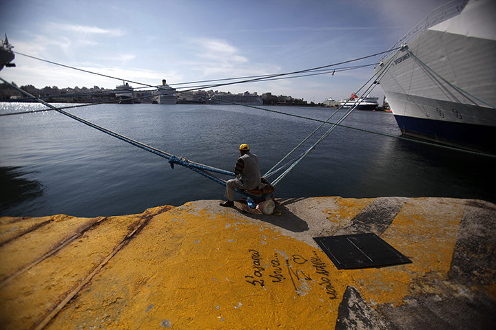 24 hours: Piraeus, Greece: A fisherman sits next to a ship during a seamen's strike