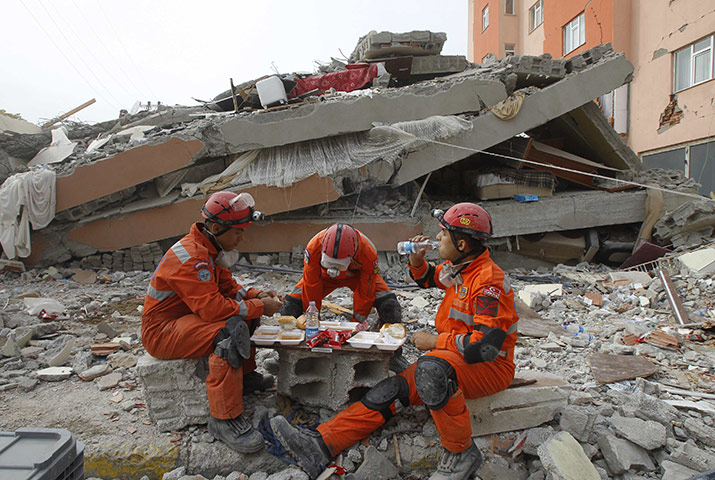 Turkey earthquake: Rescue workers rest near a collapsed building in Ercis