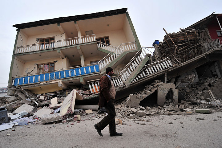 Turkey earthquake: A Turkish man walks past a collapsed building in Ercis