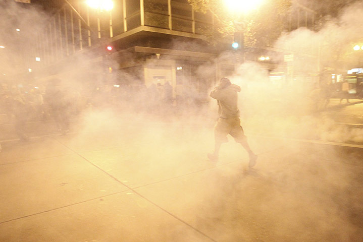 occupy oakland clashes: A masked demonstrator walks through a cloud of tear gas