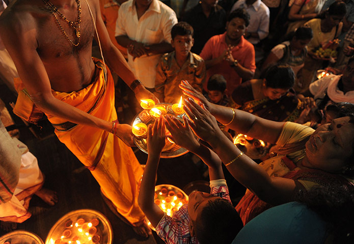 Diwali festival of lights: Sri Lankan Hindus receive blessings from a priest holding an oil lamp