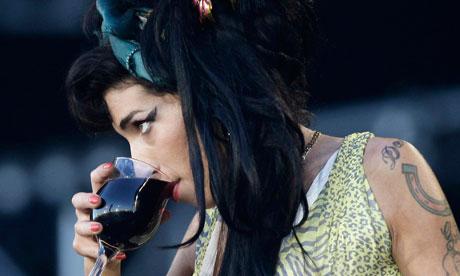 Amy Winehouse drinks from a wine glass