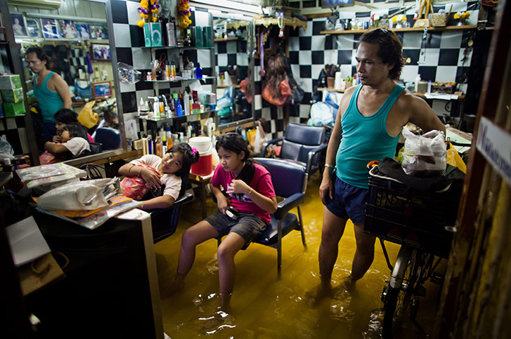 24 hours in pictures: Bangkok, Thailand: Residents watch television in a flooded beauty salon