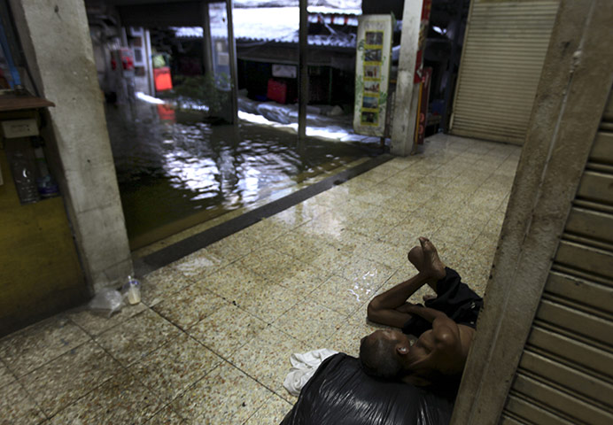 thailand flooding: A homeless man lies down at a flooded market place 