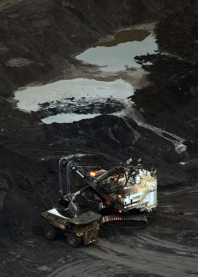 Week in Business: A large excavator loads a truck with oil sands at the Shell Albian mine