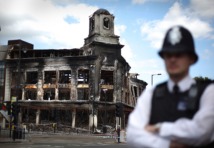 Week in Business: A police officer  stands in front of a burnt out Carpetright shop Tottenham