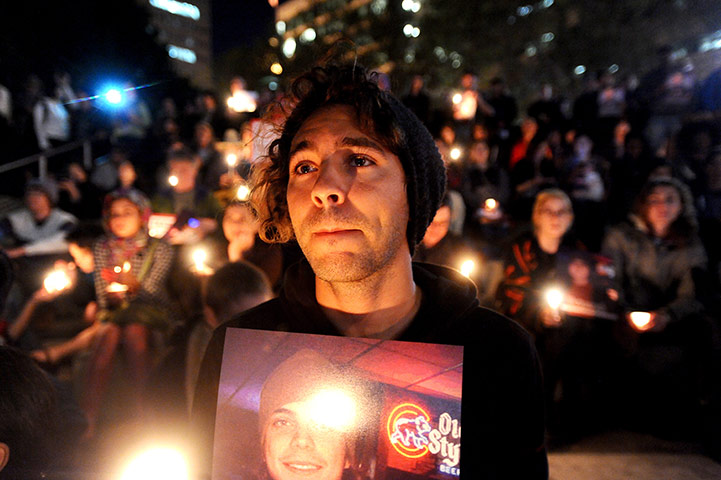 24 Hours: Oakland, US: Zachary Greer holds a photo of Scott Olsen during a vigil