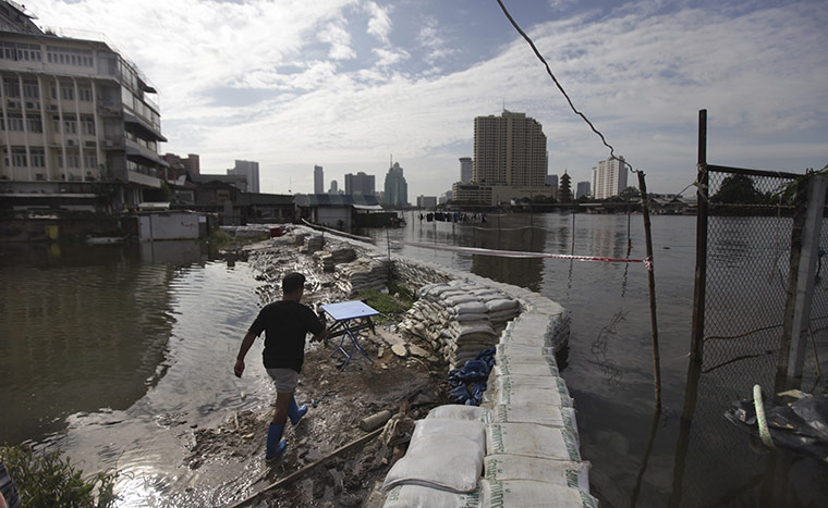 bangkok flooding: A man walks along makeshift flood defences 