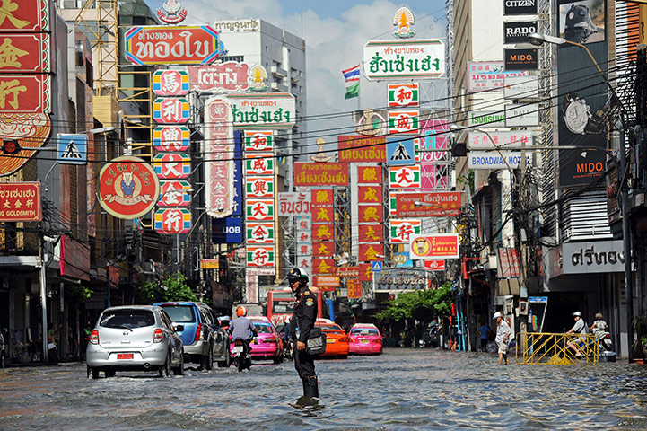 Bangkok: A policeman uses a loudspeaker to direct traffic through floodwaters 
