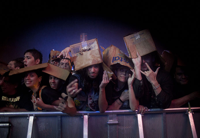 24 hours in pictures: Rio de Janeiro, Brazil: Fans protect themselves from heavy rain