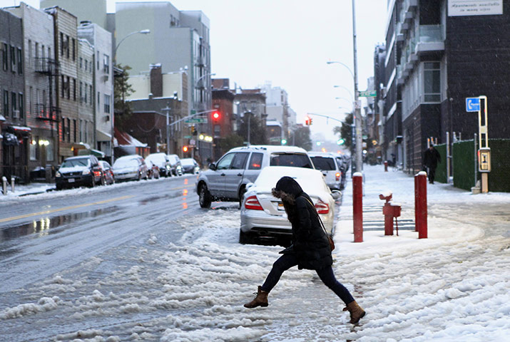 Snow in US: A woman tries to jump over a puddle during an early snow storm in New York 