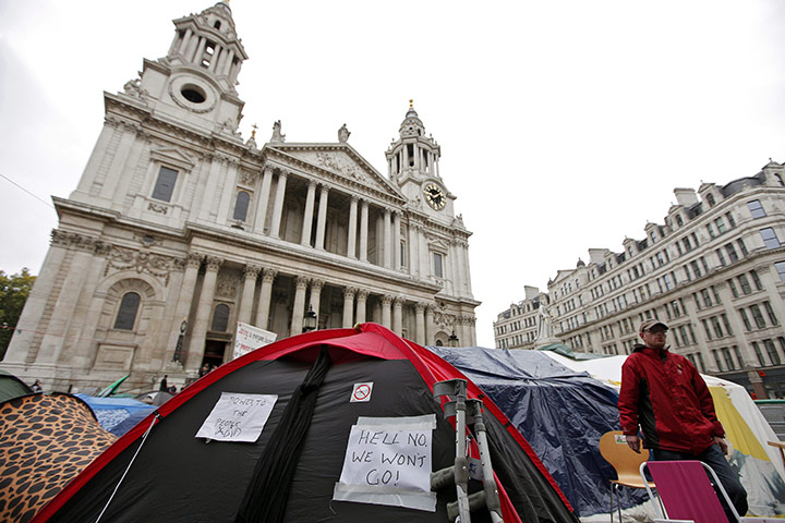 Occupy London protests: An Occupy London protester stands next to a tent with a pasted message