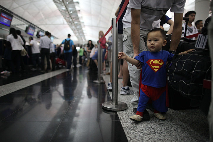 Qantas dispute: A boy dressed as superman walks between travellers waiting to check in