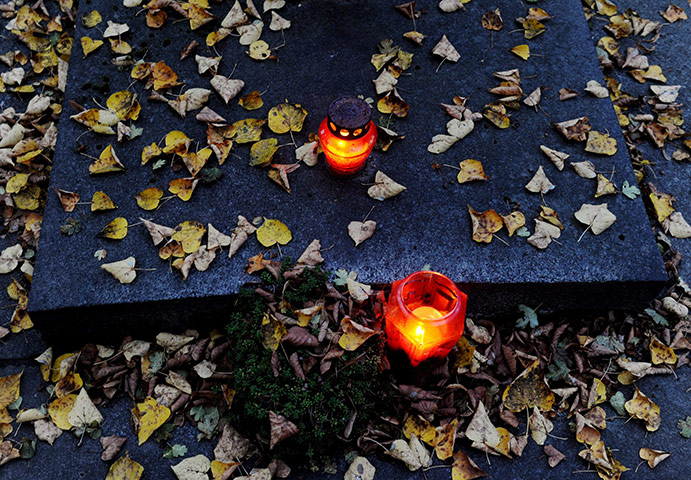 Halloween: Prague, Czech Republi: Burning candles amongst autumn leaves on a tombstone
