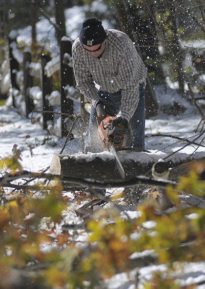 New York state snowstorm: A resident uses a chainsaw to cut up a tree that brought down a fence