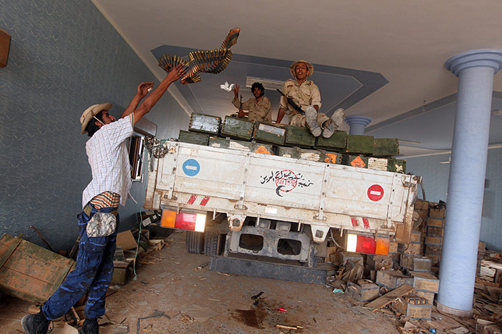 Sirte final assault: Libyan NTC fighters sit on a truck after finding a cache of weapons
