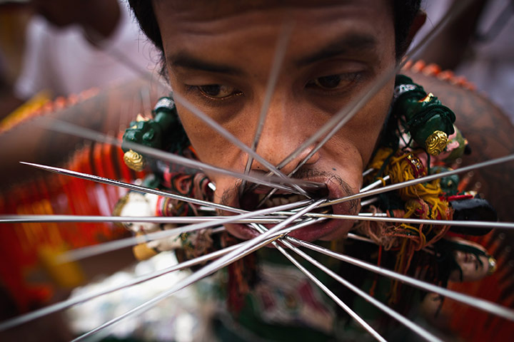 24 hours: Phuket, Thailand: A devotee pierces his cheeks with skewers