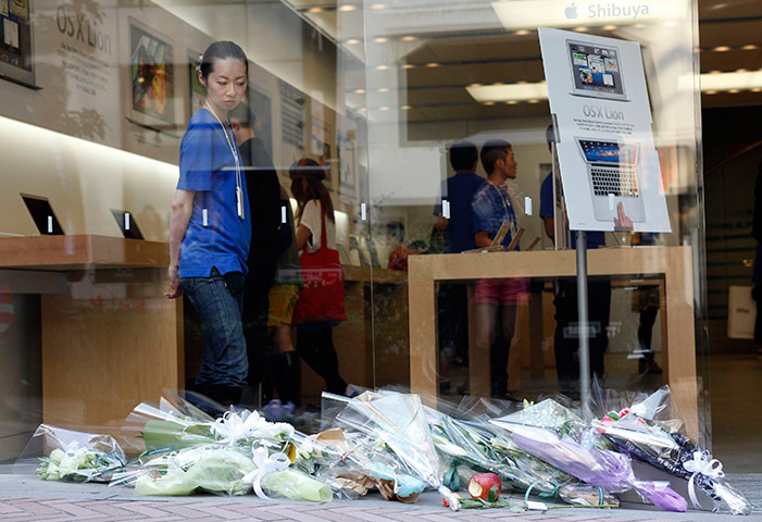 Steve Jobs Apple shrines: Tokyo, Japan: An employee looks at flowers at the Shibuya Apple store