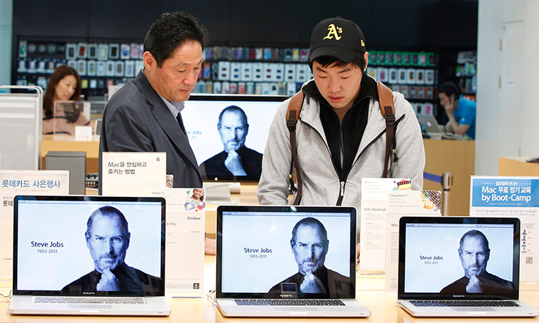 Steve Jobs Apple shrines: Seoul, South Korea: Customers look at products behind Apple computers