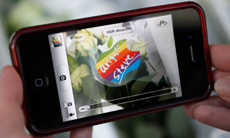 A woman uses her iPhone to do a Steve Jobs memorial