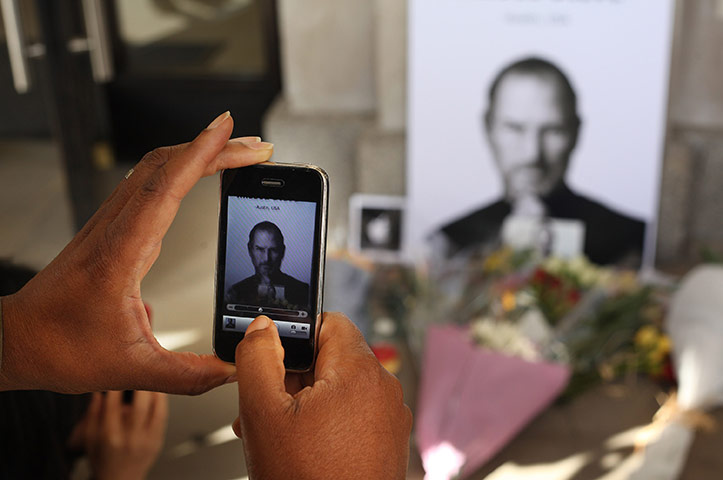 Steve Jobs tributes: London, UK: A man uses an iphone to photograph tributes to Steve Jobs