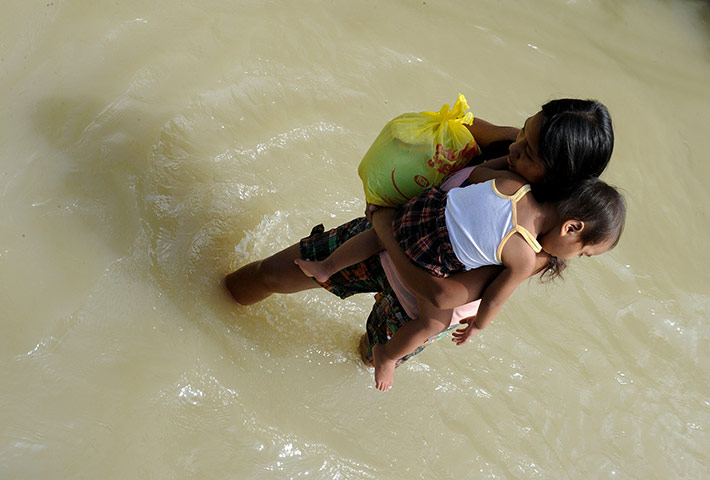 24 hours: Hagonoy, Philippines: A mother and child wade through floodwaters