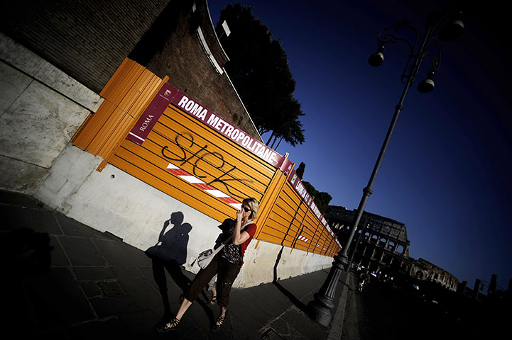 Week in Business: A woman walks past works for a new tube line near Rome's Colosseum