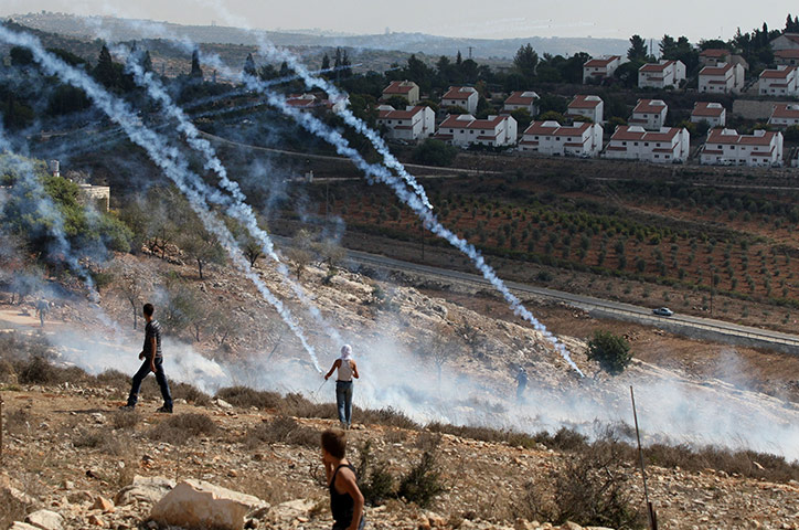 24 Hours: Palestinian stone throwers stand in tear gas smoke fired by Israeli forces
