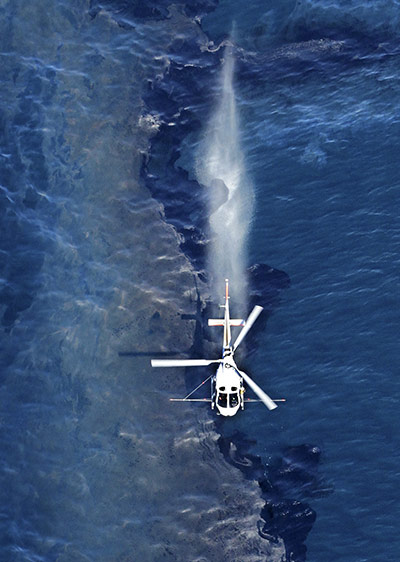 New Zealand oil spill: A helicopter sprays a dispersant on the oil slick