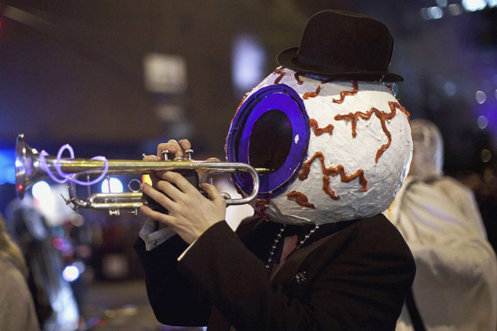 New York Halloween parade: A person dressed up in an eyeball costume plays the trumpet 