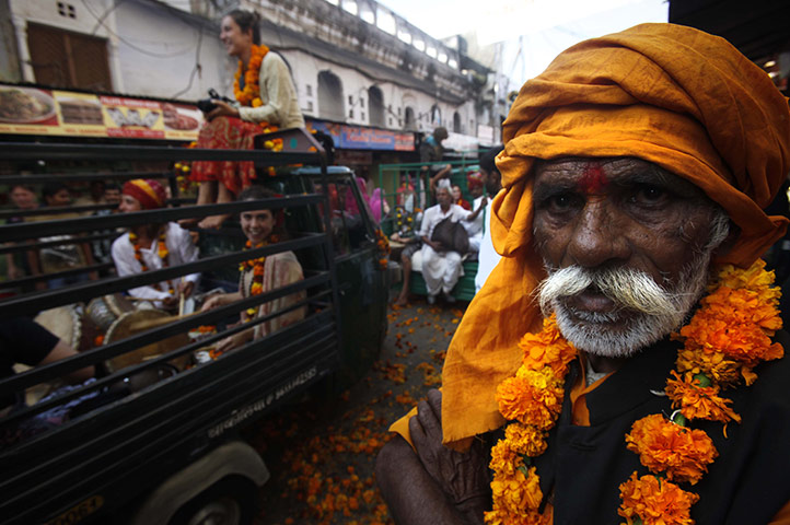 FTA: Manish Swarup: An Indian holy man watches foreign tourists participate in a spiritual walk
