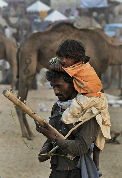 FTA: Manish Swarup: A musician plays a Rajasthani instrument while carrying his daughter 
