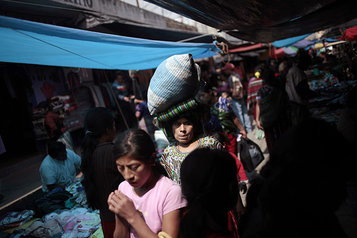 24 hours in pictures: A woman walks in a market Nebaj, Guartamala