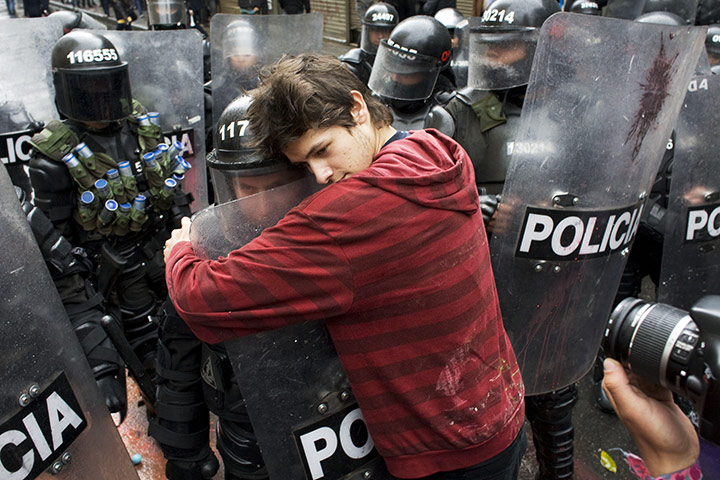 24 hours in pictures: Bogota, Colombia: A demonstrator embraces a riot police officer