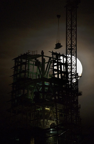 24 Hours: A silhouette of a workman in front of the moon above the Shard building