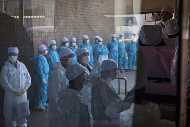 24 Hours: Employees of Tokyo Electric Power Co wait for a bus at Fukushima