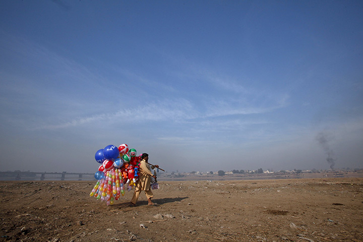 24 hours in pictures: A man carries balloons for sale near the banks of the Ravi river in Lahore
