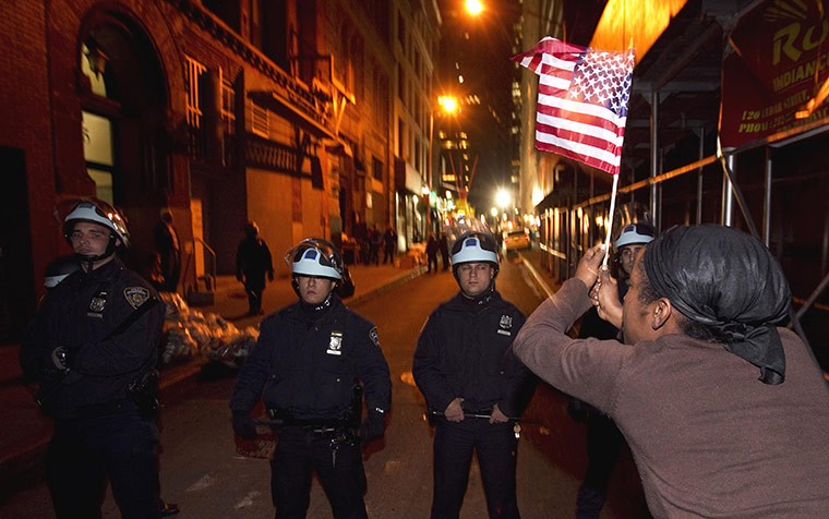 occupy wall street: A member of the Occupy Wall St movementwaves the stars and stripes