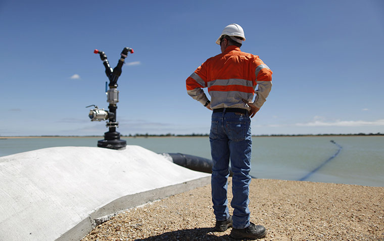 From the agencies: A worker stands at the edge of an untreated water at a QGC reverse