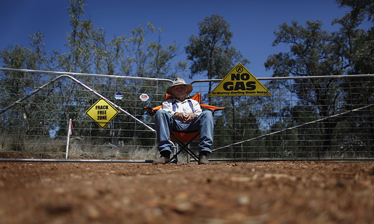 From the agencies: Farmer sits in front of an access gate owned by coal seam gas miner Santos