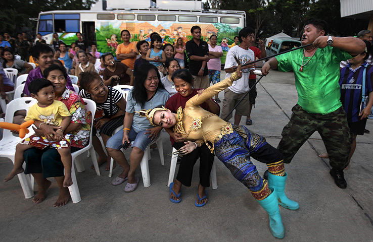 24 hours in pictures: A Thai soldier, dressed in a traditional costume, entertains flood victims