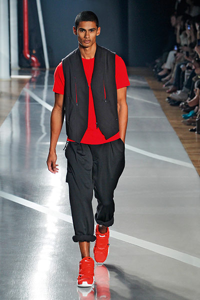 Skateboarding Fashion: man in red t-shirt, long shorts.