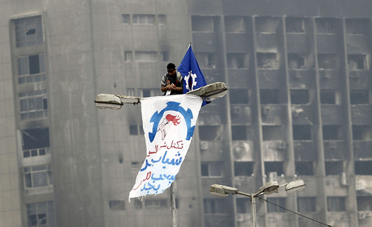 Tahrir, Egypt: A man takes part in Friday prayers while on top of a pole at Tahrir Square