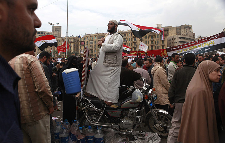 Tahrir, Egypt: A man stands on his motorbike as he attends a mass protest at Tahrir Square