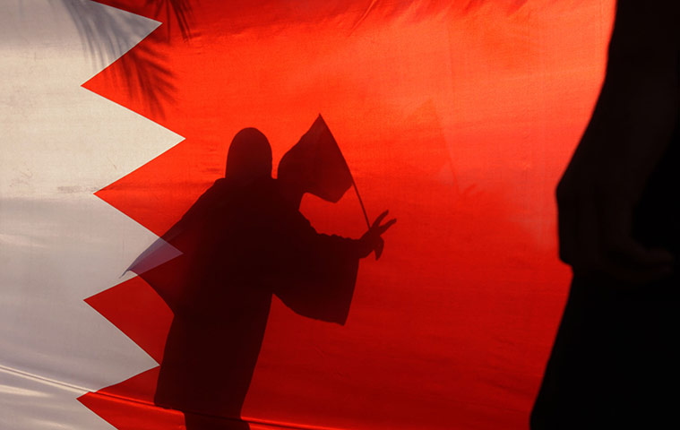 24 hours: A woman carrying a national flag is seen gesturing behind a Bahraini flag