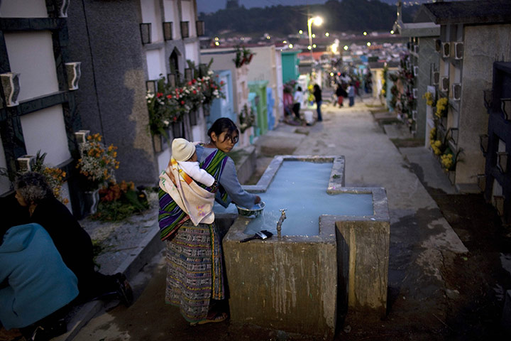All saints day: A woman fills a jug with water for flowers to decorate graves, Guatemala